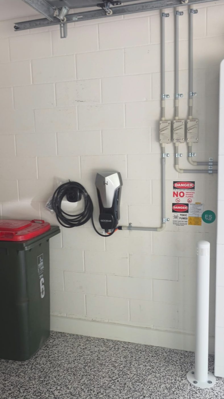 Wall-mounted EV charger with coiled cable installed in a Brisbane garage
